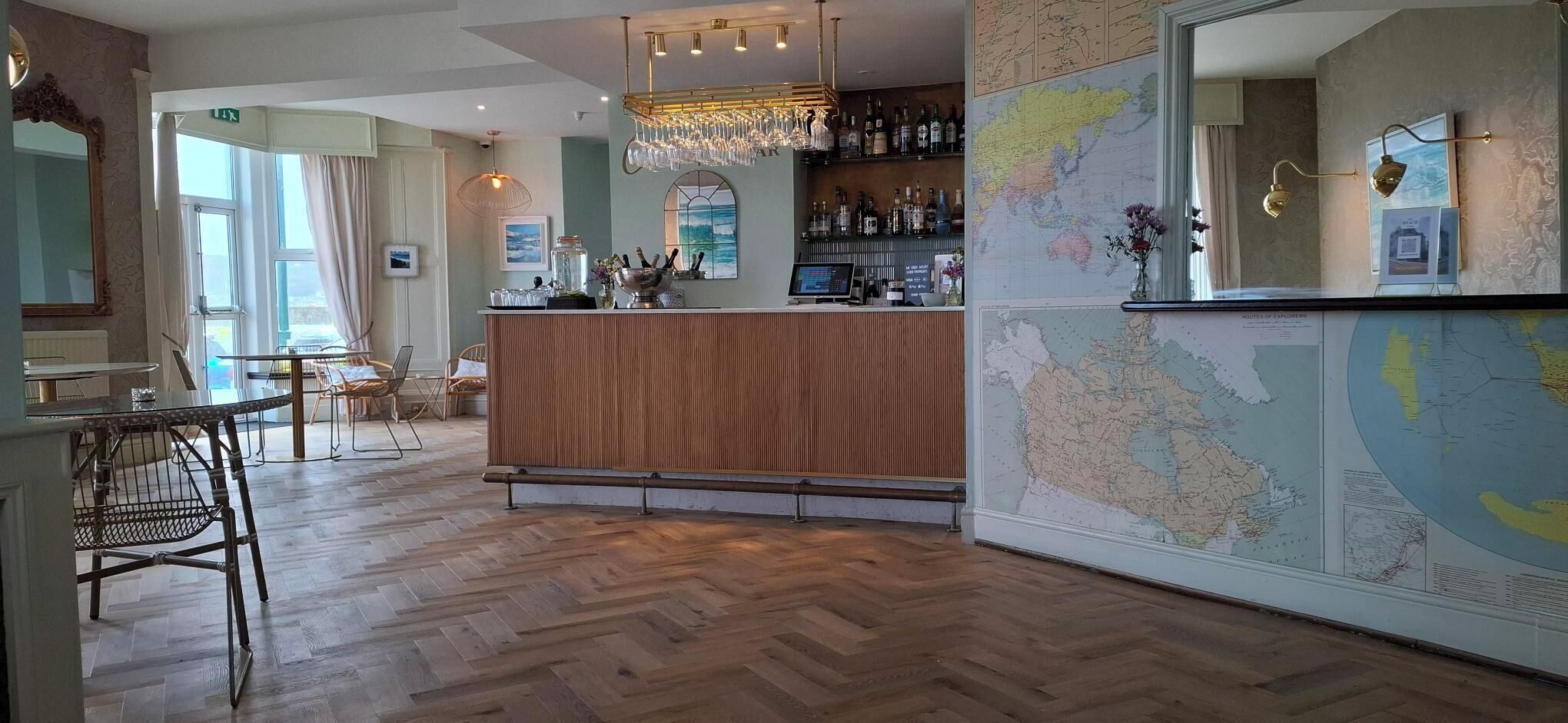 A bar area with a wooden counter, a map on the wall, and a seating area with chairs and tables.