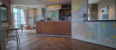 A bar area with a wooden counter, a map on the wall, and a seating area with chairs and tables.