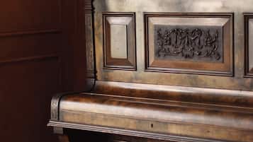 A wooden piano with a brass bowl on top, a book titled 'The Russian Century,' and a small brochure on the right.