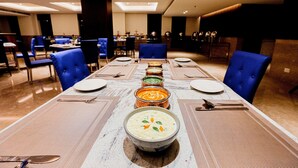 Un espace repas avec une longue table dressée pour un repas, entourée de chaises bleues.
