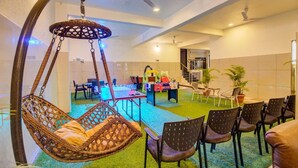 Una habitación con una silla colgante, una mesa con sillas y una piscina pequeña.