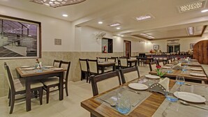 Comedor con varias mesas dispuestas para recibir a los huéspedes, con sillas y cubertería.