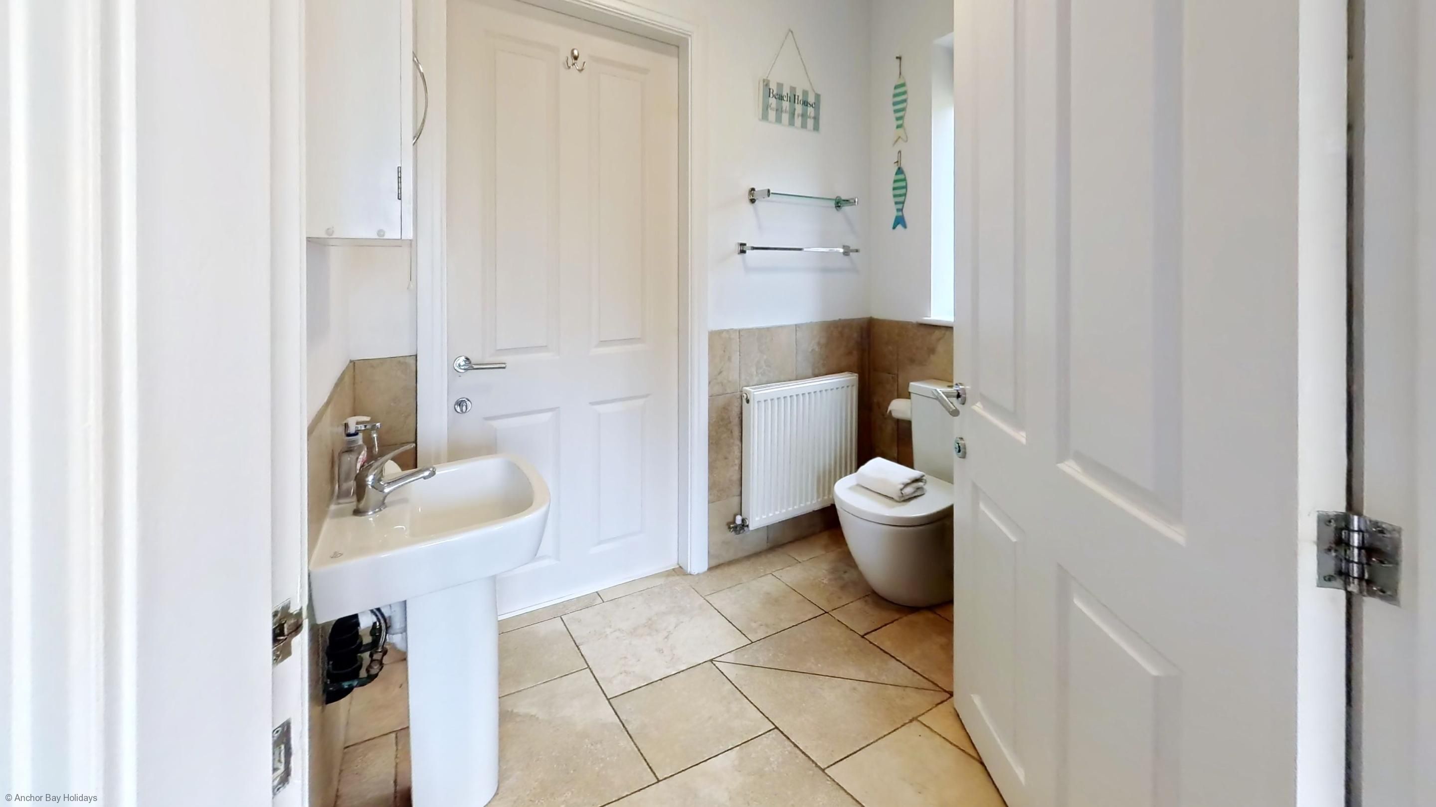 Un baño con lavamanos, inodoro y radiador blancos.
