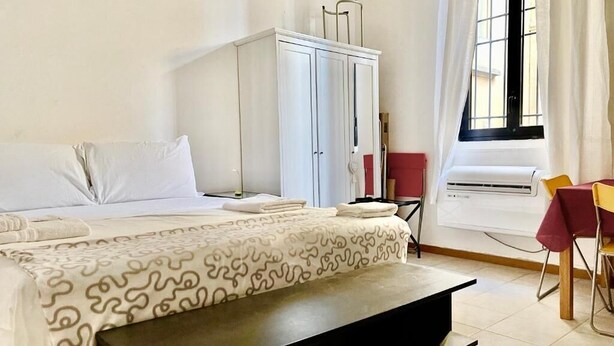 Quarto de hotel com cama, guarda-roupa, escrivaninha e ar condicionado.