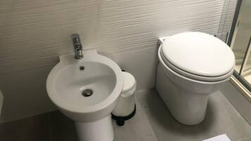 City studio | Badkamer | Een bad, een haardroger, een bidet, handdoeken