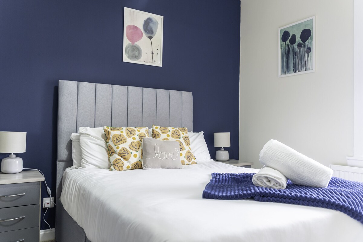 A neatly made bed with white bedding, a grey headboard, and decorative pillows.
