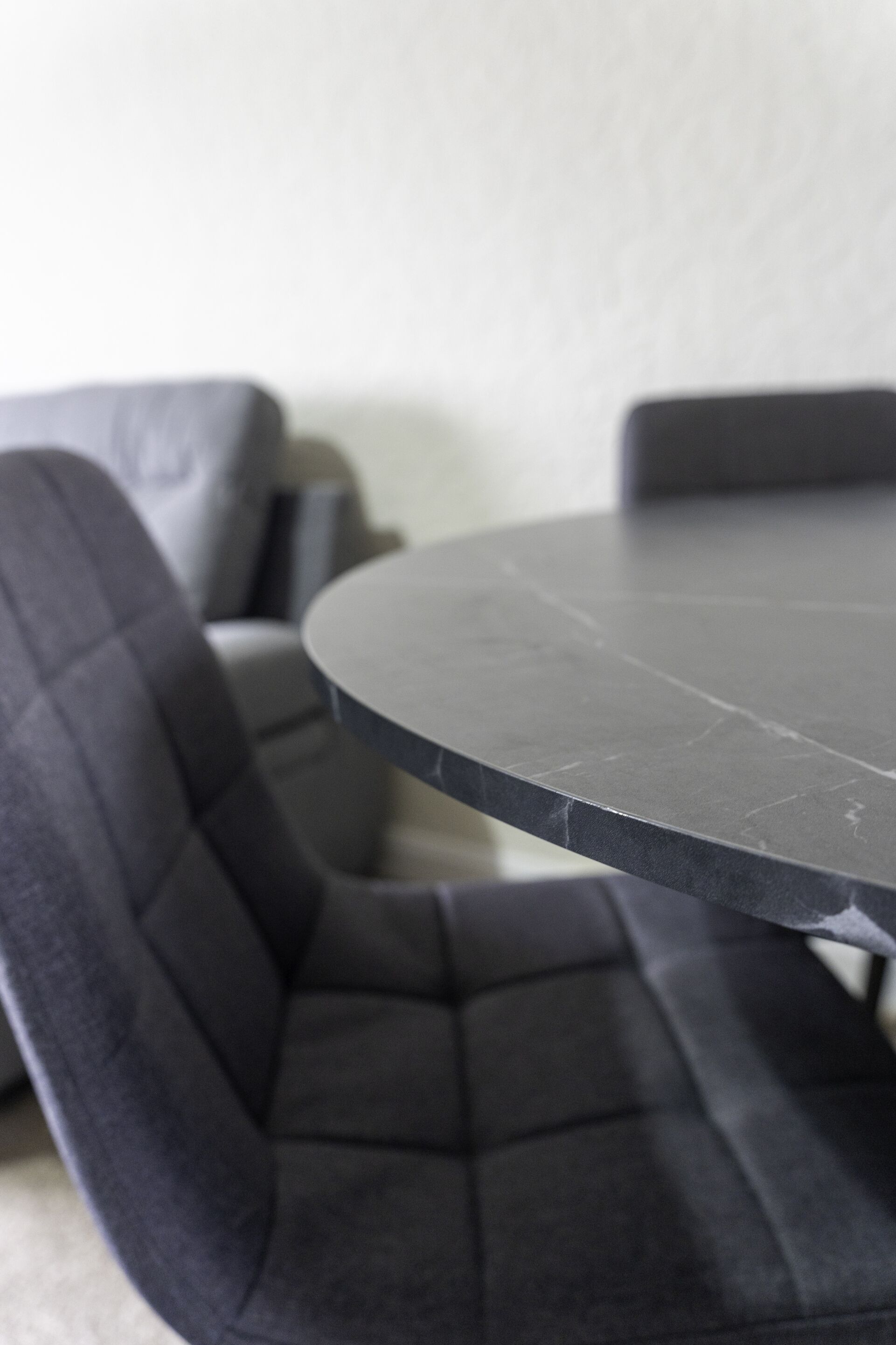 A round table with a dark surface and a single chair with a dark cushion.