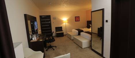 Una habitación de hotel con escritorio, silla, sofá y un espejo grande.