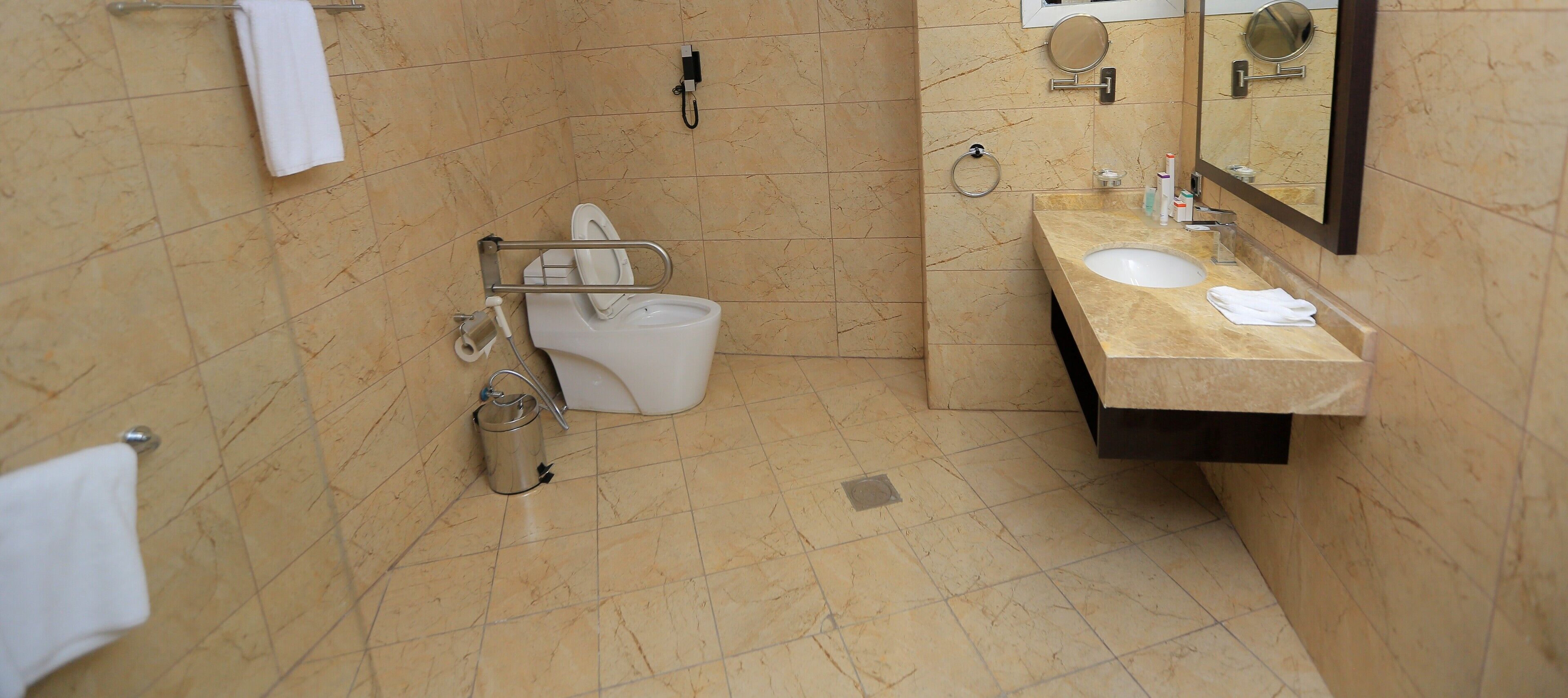 A bathroom with a toilet, sink, and mirrors.