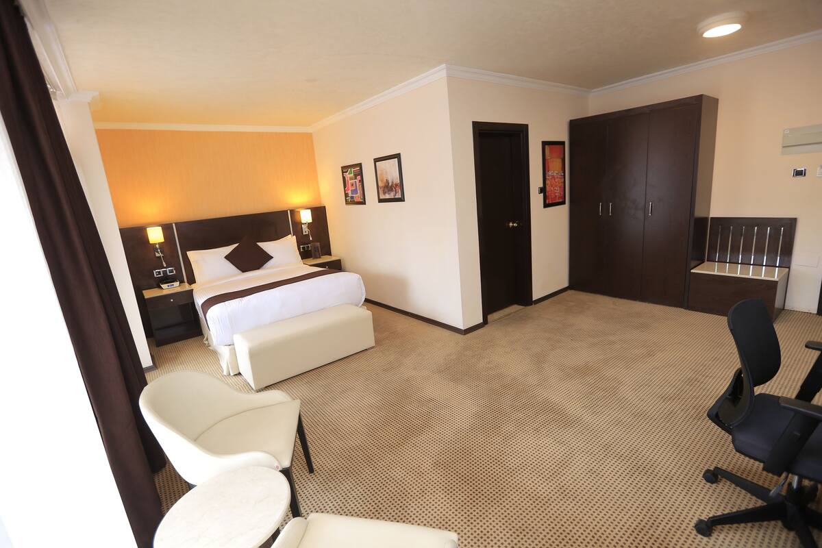 A hotel room with a bed, a desk, a chair, and a wardrobe.