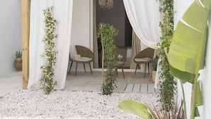 A patio with white curtains, wicker furniture, and potted plants. - 120 Hotel Boutique (Ciutadella de Menorca)
