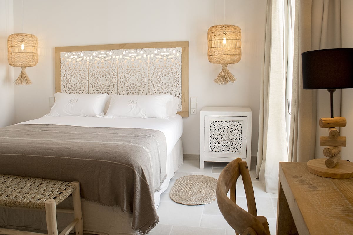 A bedroom with a bed, bedside tables, a chair, a lamp, and a decorative wall panel.
