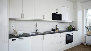 Cocina moderna con armarios blancos, encimera negra, horno integrado y ventana que proporciona luz natural.