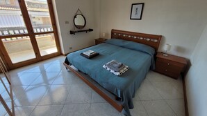 Una camera da letto con un letto, un comodino, una lampada da comodino, uno specchio fissato alla parete e un quadro incorniciato.