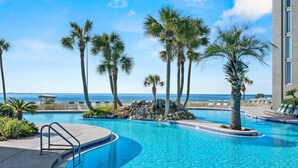 A swimming pool with palm trees and a view of the ocean. - Stunning oceanfront condo in Panama City Beach, perfect for up to 8 guests! (Panama City Beach)