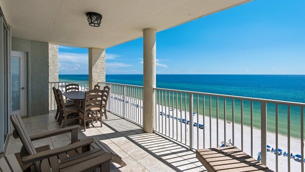 A covered outdoor area with a table and chairs, a view of the ocean, and a railing. - Stunning oceanfront condo in Panama City Beach, perfect for up to 8 guests! (Panama City Beach)