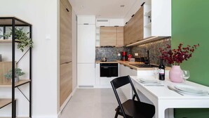 A modern kitchen with white cabinetry, a dining table set for two, and a coffee machine.