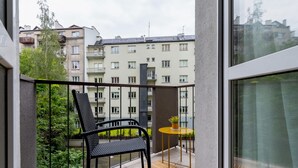 A balcony with a chair and a small table, overlooking a residential area with multi-story buildings.