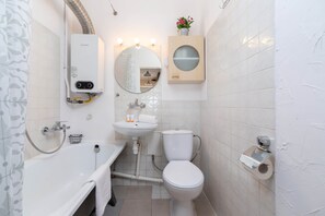 A modern bathroom with a bathtub, toilet, sink, and a built-in heater.