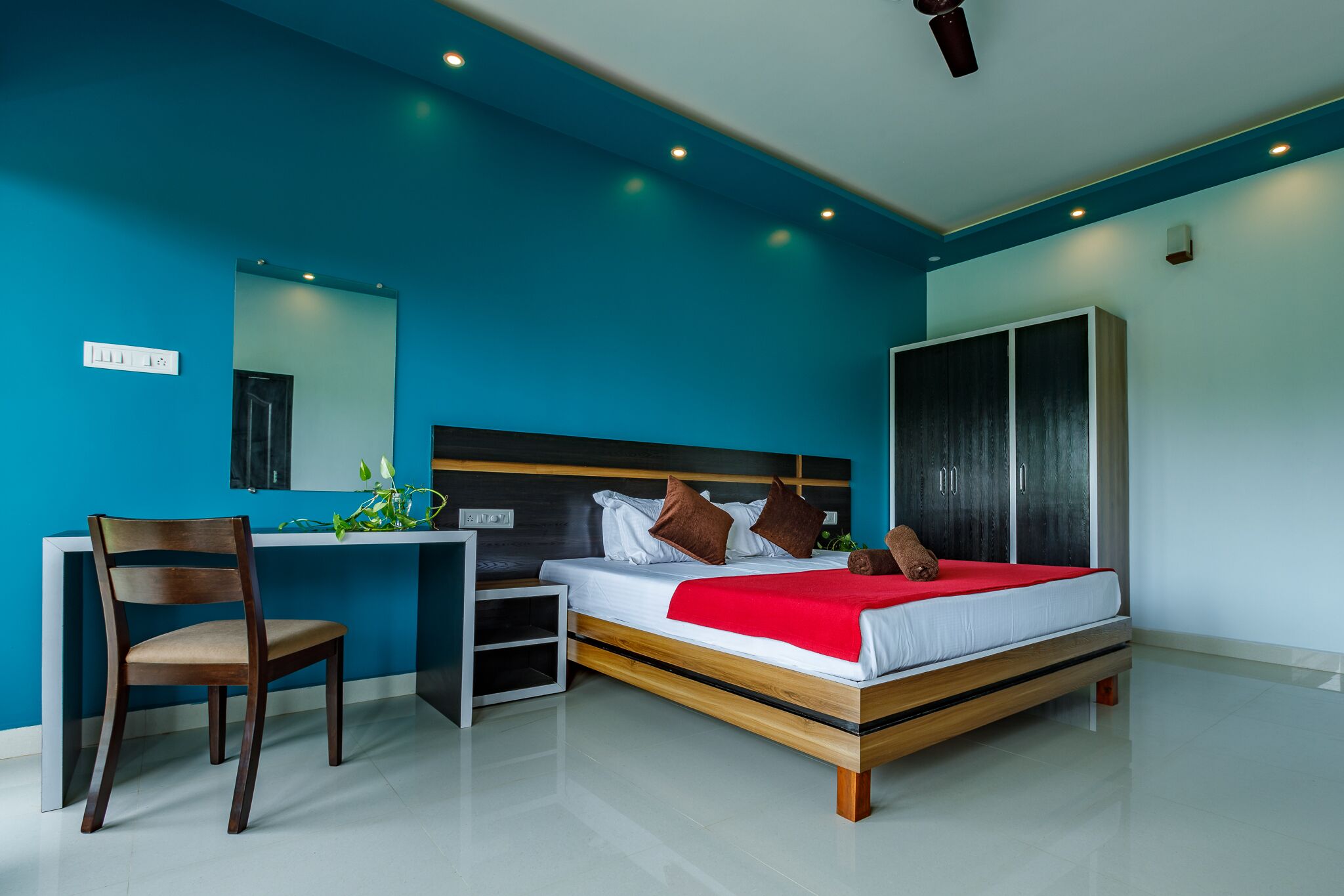 A modern bedroom with a bed, desk, chair, and wardrobe.