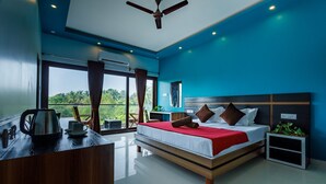 Un dormitorio moderno con una cama grande, un escritorio con hervidor y vistas a zonas verdes.