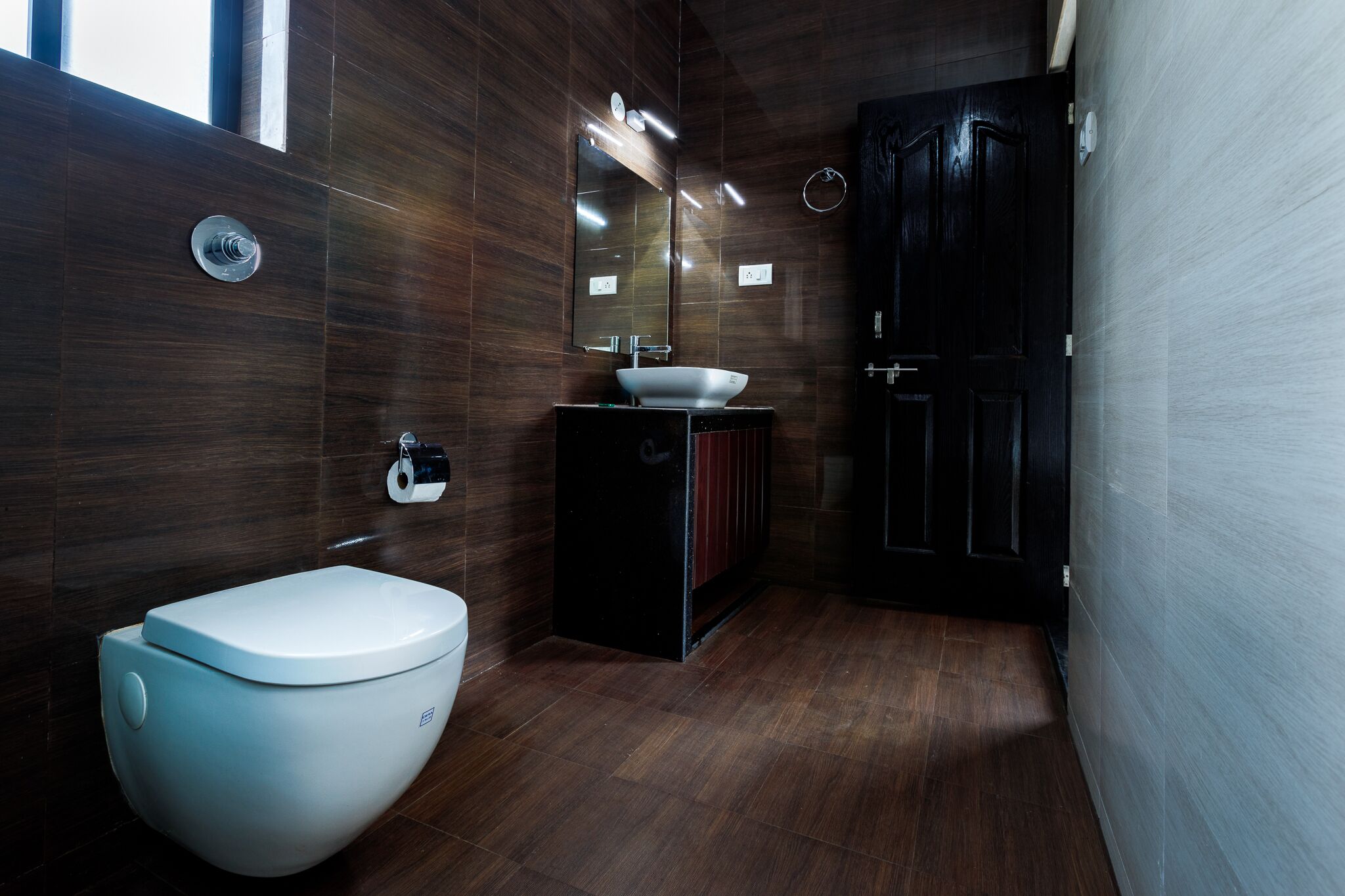 Un baño moderno con inodoro, lavamanos y espejo.