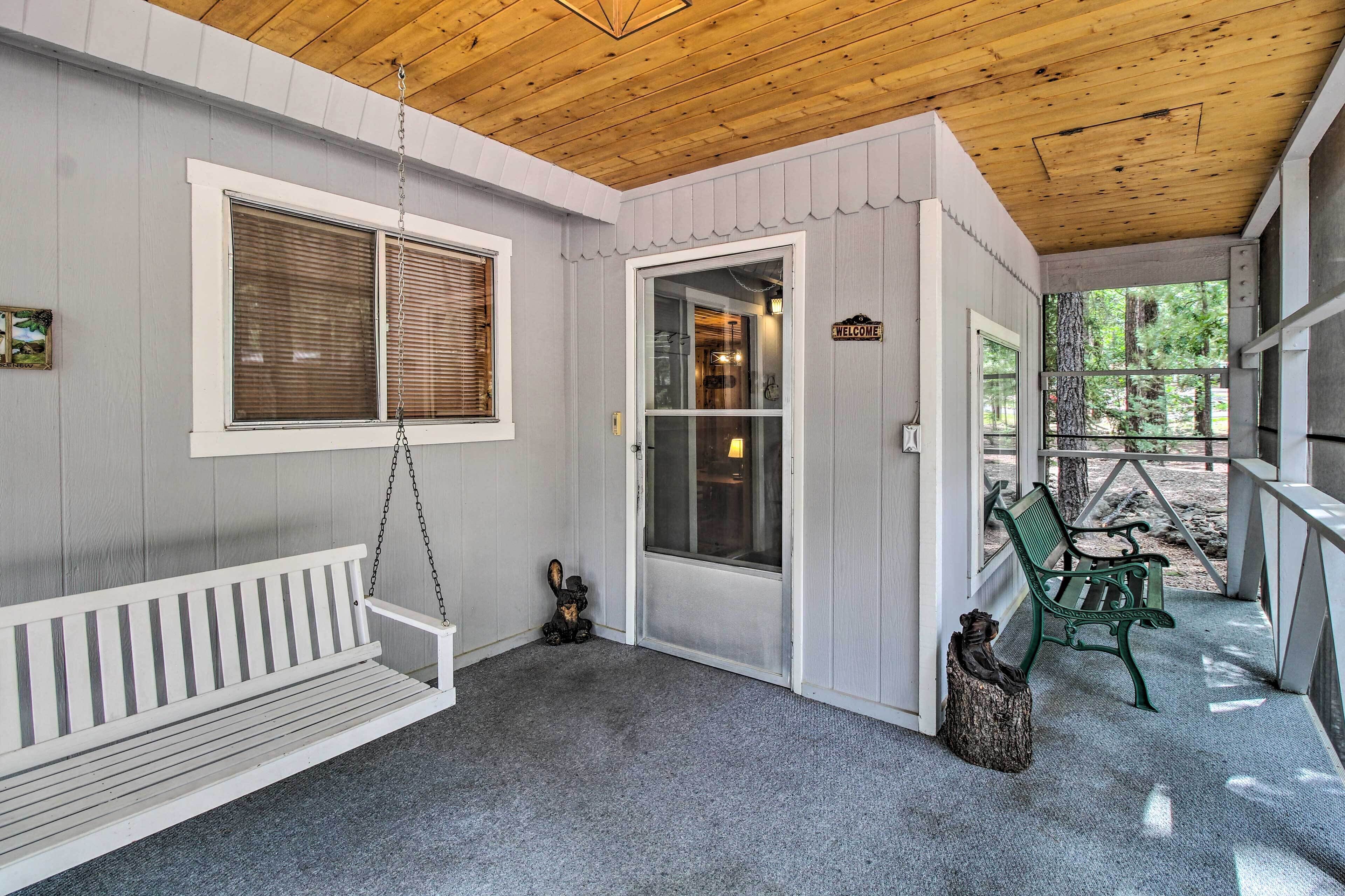 A covered porch with a bench, a swing, and a welcome sign.