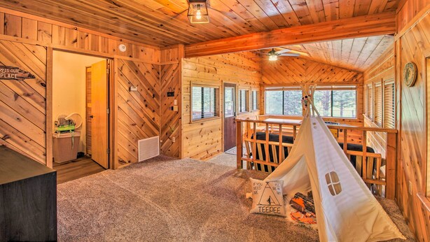 Un interno accogliente di una baita con arredamento in legno, una tenda a cono e vista sull'esterno.