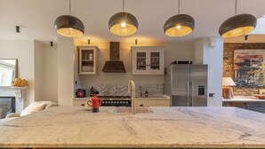 A modern kitchen with a marble countertop, stainless steel appliances, and pendant lighting.