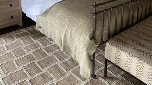 A neatly arranged bedroom with a bed, bedside tables, lamps, and a patterned rug. - Simbavati River Sands (Bushbuckridge)