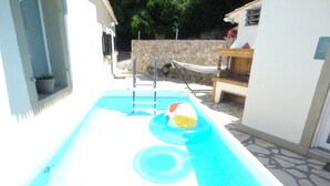 A rectangular swimming pool with a ladder, a hammock, and a stone wall in the background. - Lovely Studio in Strinilas With its own Pool (Corfu)