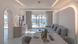 Una habitación de hotel moderna con zona de comedor, sofá y vistas al océano.