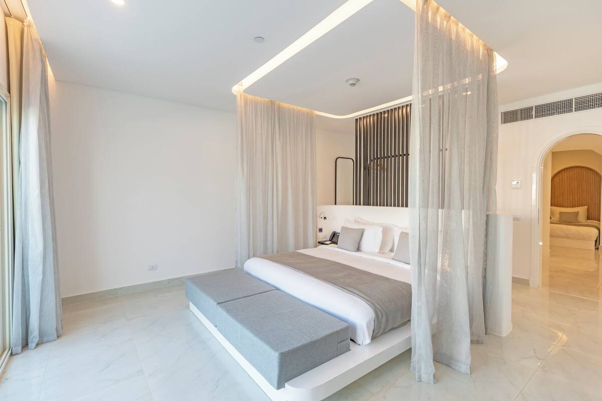 A modern bedroom with a canopy bed, a bedside table, and a built-in bench.