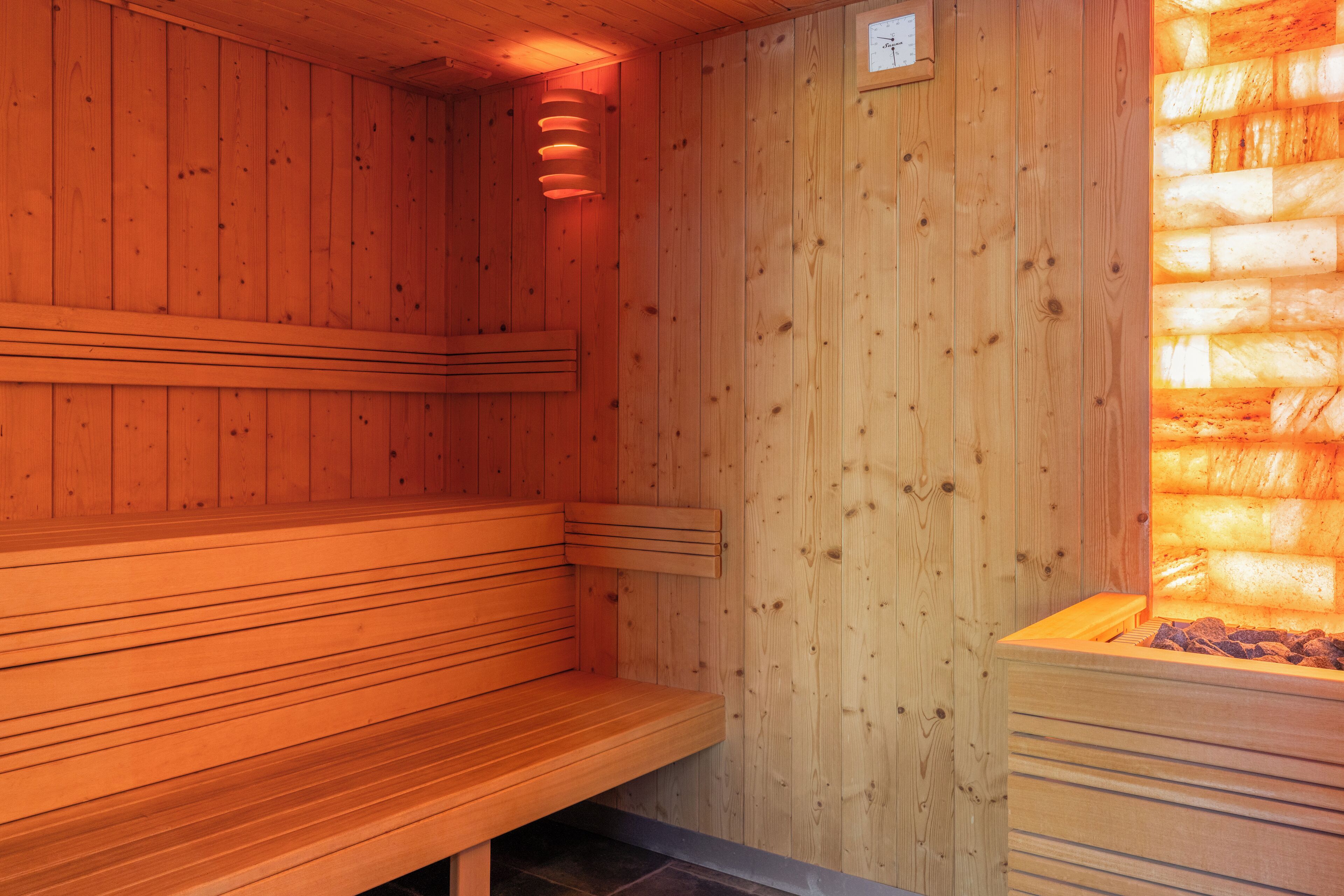 Eine Holzsauna mit Bänken und einer sichtbaren Wärmequelle.