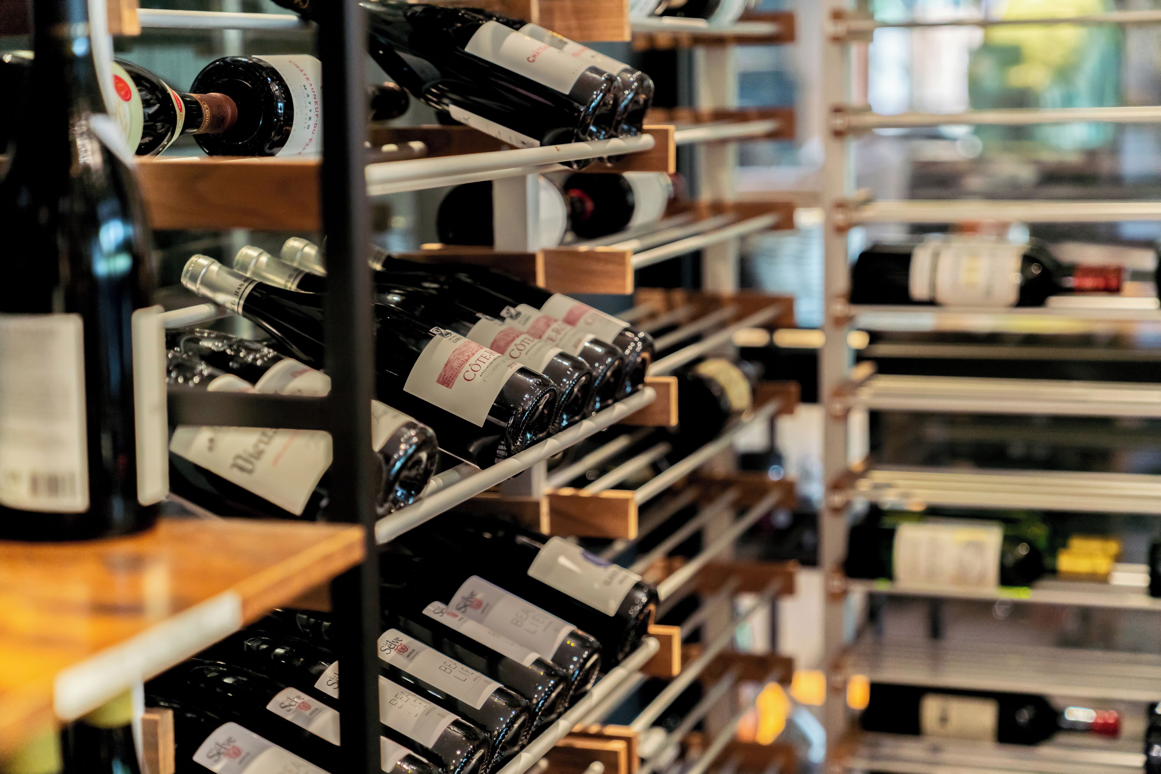 A wine rack with multiple bottles, each labeled with a cork.