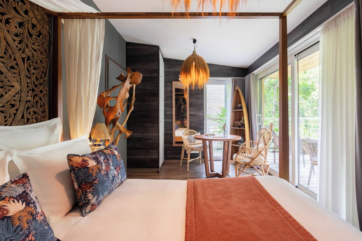 Un dormitorio amplio con una cama grande, un comedor con sillas y vistas al exterior.