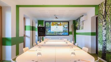 A conference room with a long table, chairs, and a screen displaying a welcome message.