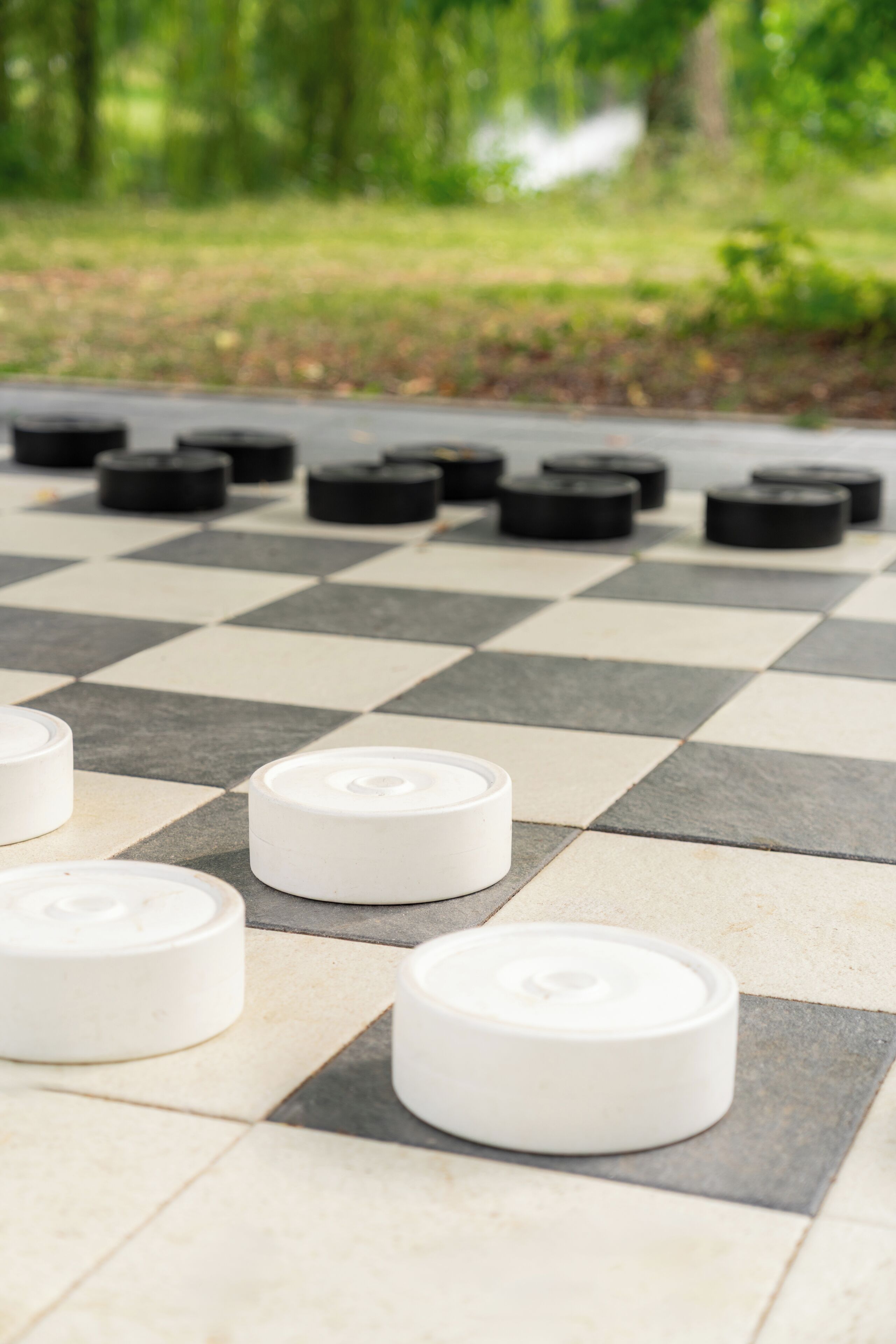 Un jeu d’extérieur dont le plateau est à carreaux, avec des pièces blanches et noires.