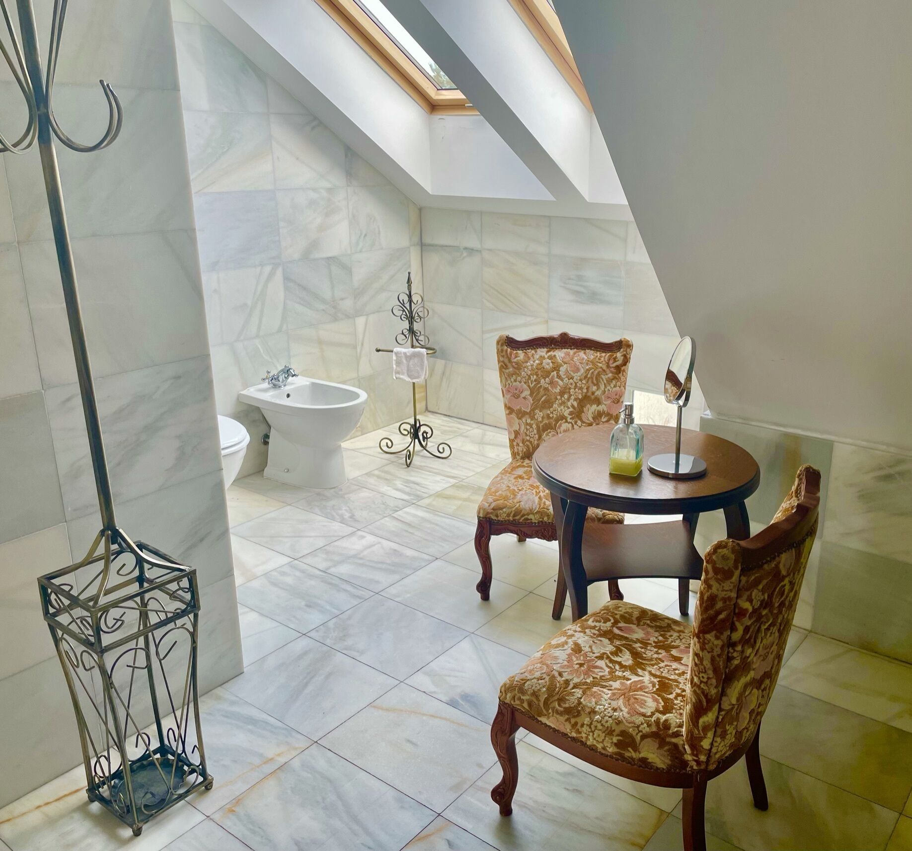 A bathroom with a bathtub, a bidet, and a toilet. There is a round table with chairs and a small decorative item on it.