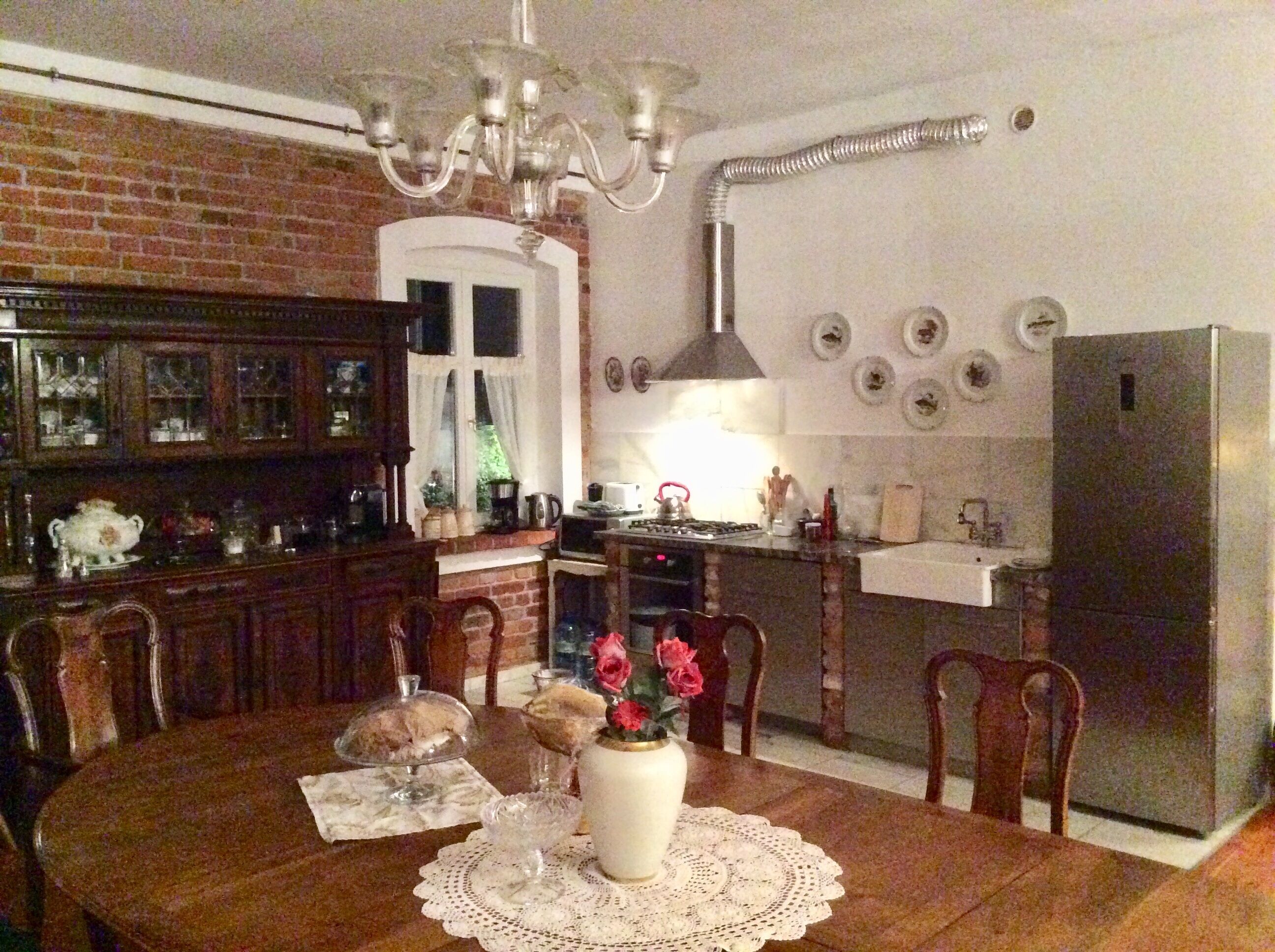 A dining table with chairs, a vase with flowers, and a chandelier.