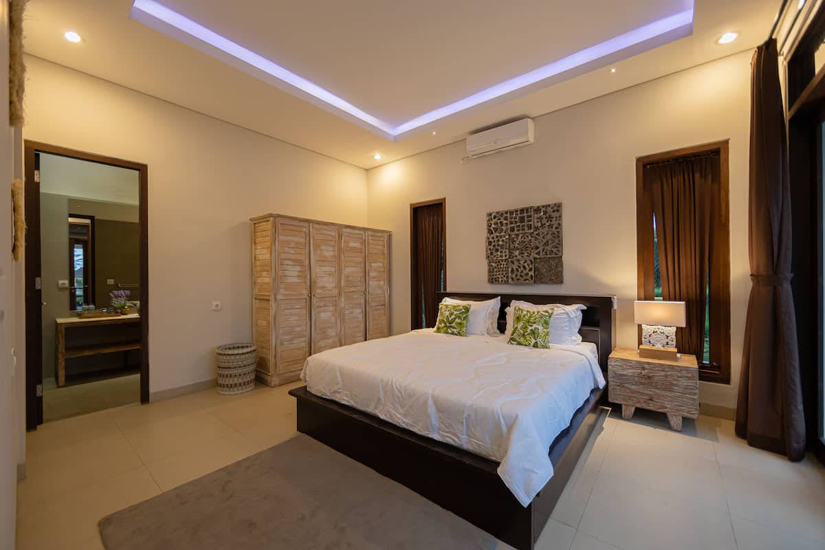 Une chambre à coucher moderne avec un grand lit, une table de chevet en bois, un miroir et une armoire.