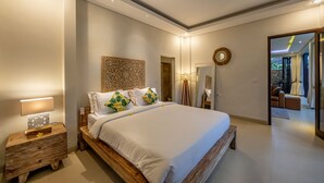 A modern bedroom with a large bed, bedside tables, a nightstand, a decorative wall piece, and a mirror. - Green Oasis Private Villa (Ubud)