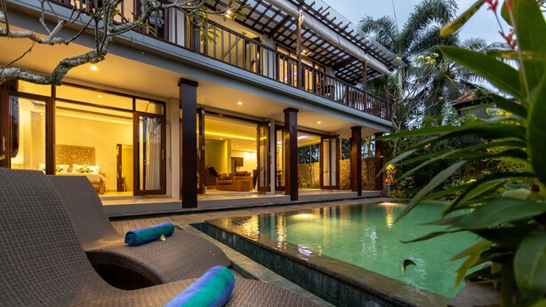 A poolside area with lounge chairs and a pool, surrounded by lush greenery. - Green Oasis Private Villa (Ubud)
