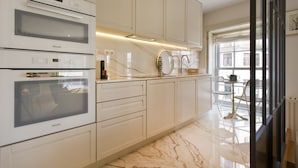 A modern kitchen with a built-in oven, a marble countertop, and a view of the city through large windows. - Amazing 2 Bedroom Apt w/ Great Views, 2 min Walk From Douro River in City Center (Porto)