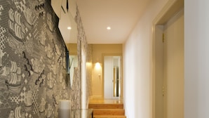 A hallway with patterned wallpaper, a glass table, wooden flooring, and a staircase leading to another room. - Amazing 2 Bedroom Apt w/ Great Views, 2 min Walk From Douro River in City Center (Porto)