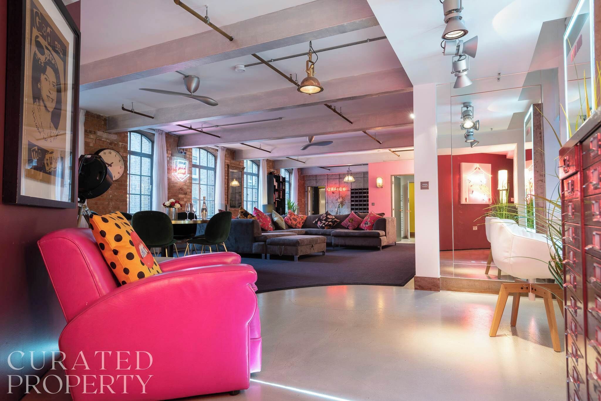 Eine geräumige Lobby mit modernem Design, ausgestattet mit einem rosafarbenen Sofa, einem Holzstuhl und einer Sitzecke mit Sofa und Sesseln.