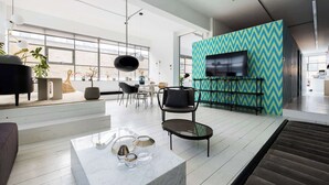 Un interno moderno con una grande televisione, un muro decorato con motivi e un’area salotto con tavolino.