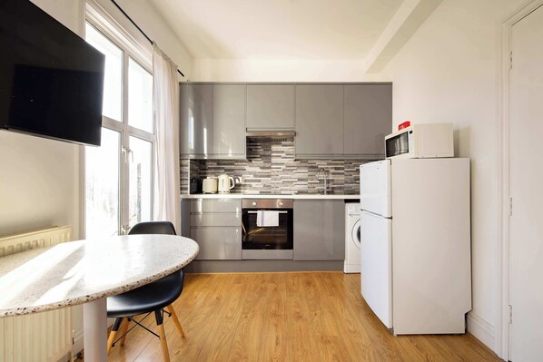 A compact kitchen with a built-in oven, a microwave, and a washing machine.