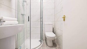 A modern bathroom with a glass-enclosed shower, a white sink, and a toilet.