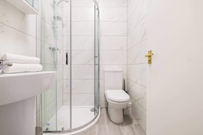 A modern bathroom with a glass-enclosed shower, a white sink, and a toilet. - 1 Bedroom Flat - Shepherds Bush (Greater London)